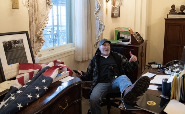 Man Photographed Sitting With Foot Up On US House Speaker's Desk Arrested