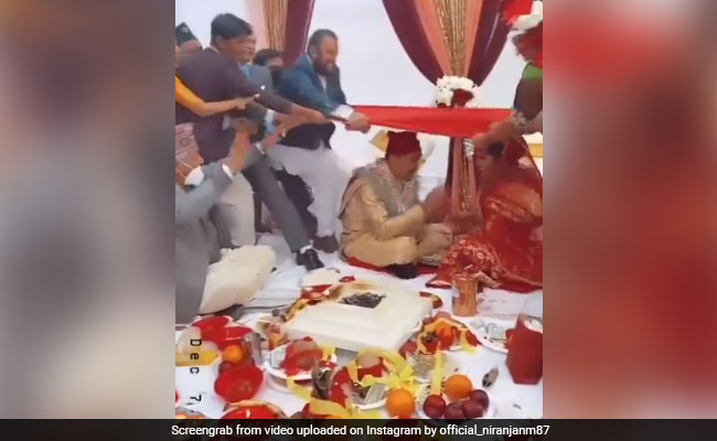 शादी की रस्म के बीच हुआ कुछ ऐसा, धड़-धड़ाकर दूल्हा-दुल्हन के ऊपर गिरे सभी मेहमान, लोग बोले- बड़ा बेहूदा रिवाज़ है - देखें Video