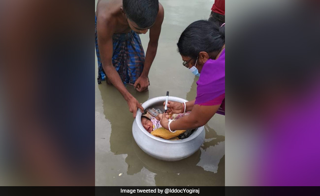 बाढ़ के पानी के बीच नवजात बच्चे को  बर्तन में लिटाकर दी गई पोलियो खुराक, लोग कर रहे हेल्थ वर्कर की तारीफ - Viral Photo
