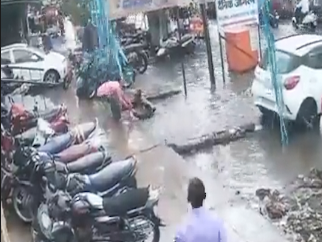 पानी से लबालब सड़क पर पुलिसकर्मी और उसकी पत्नी नाले में गिरे