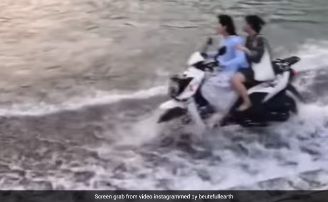 उफनती नदी के बीच लड़की ने दौड़ा दी स्कूटी, लोग बोले- पापा की परी है, उड़ के भी जा सकती थी