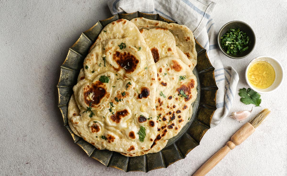 Sprinkle some chopped garlic, coriander leaves and kalonji on your garlic naan.