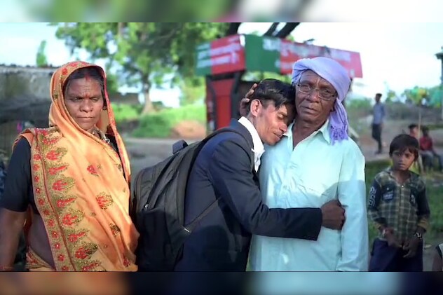 चित्र में अपने पिता के कंधे पर सिर रखकर भावुक हुआ आदिवासी युवक आसाराम.