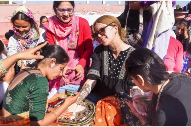 बीकानेर ऊंट महोत्सव में एक विदेशी पर्यटक के हाथों में मेहंदी लगाती महिलाएं. बीकानेर ऊंट महोत्सव में एक विदेशी पर्यटक के हाथों में मेहंदी लगाती महिलाएं.