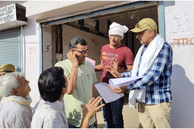 मौके पर मौजूद अधिकारियों को कागज दिखाते हुए स्थानीय दुकानदार. मौके पर मौजूद अधिकारियों को कागज दिखाते हुए स्थानीय दुकानदार.