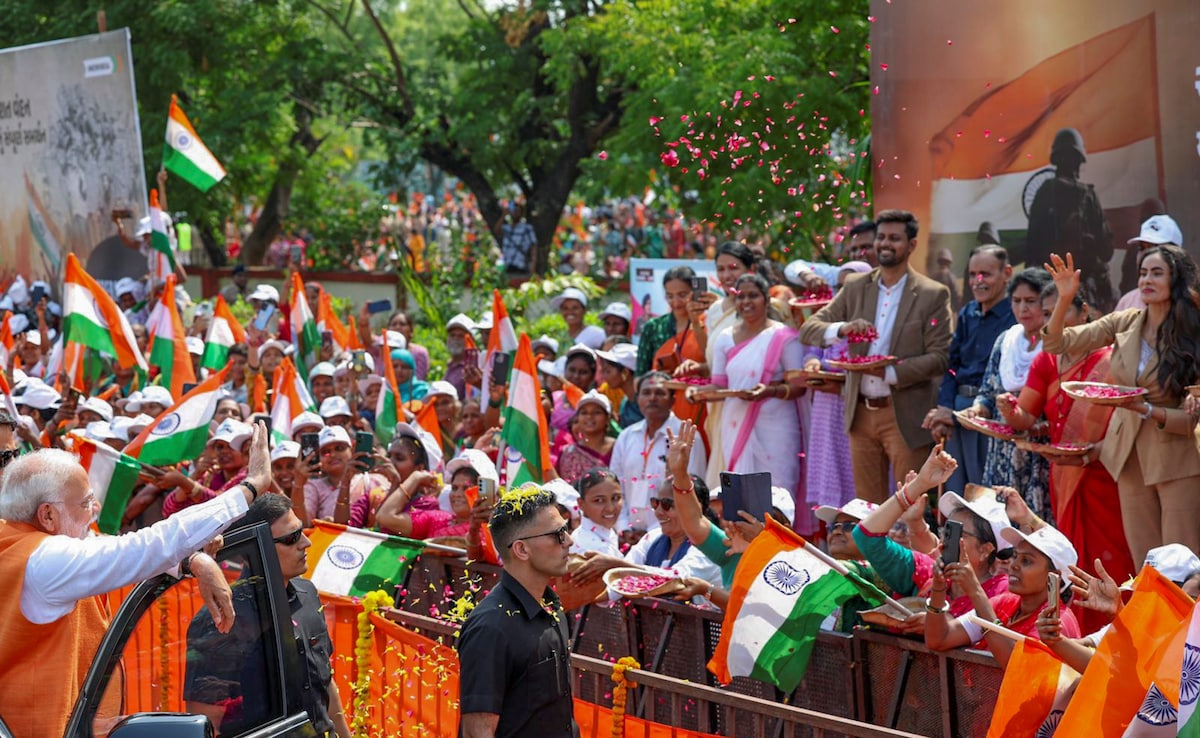 Family members of Army officer Colonel Sofiya Qureshi shower flower petals on PM Modi as he waves at supporters during the roadshow. 