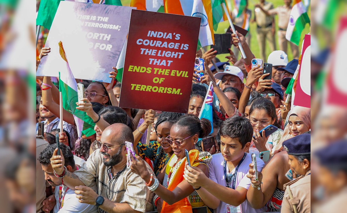 People hold placards, click pictures as PM Modi waves at them during the roadshow. 