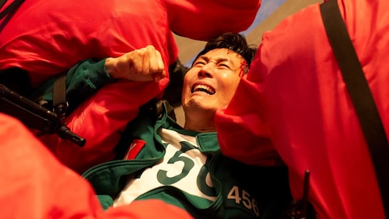 Gi-hun being forcibly taken by a masked guard in a scene from Squid Game Season 3