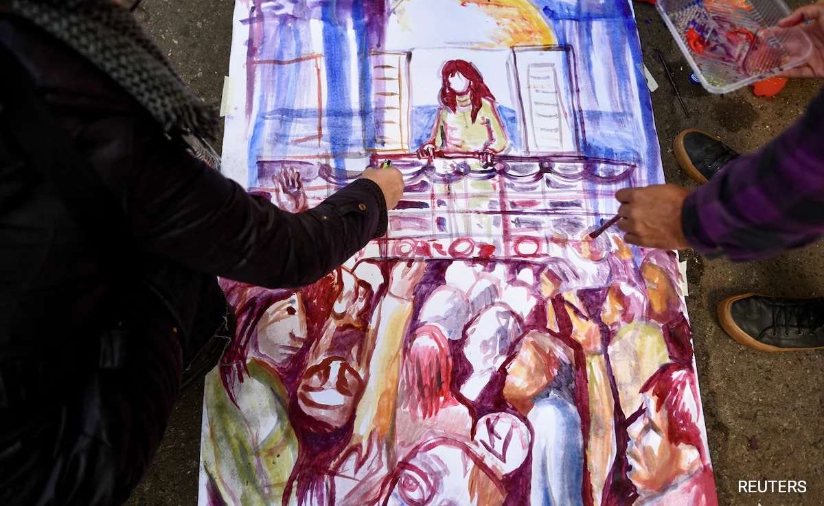 на жилищна улица Буенос Айрес двама протестиращи рисуваха разказващо изображение