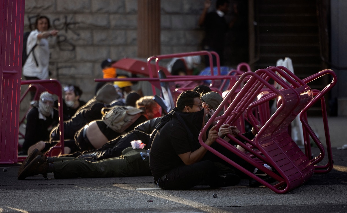 Demonstrators take cover behind a makeshift barricade as Los Angeles police officers shoot at them with non lethal ammunitions as clashes erupt next to City Hall during a protest (Source: AFP) Demonstrators take cover behind a makeshift barricade as Los Angeles police officers shoot at them with non lethal ammunitions as clashes erupt next to City Hall during a protest (Source: AFP)