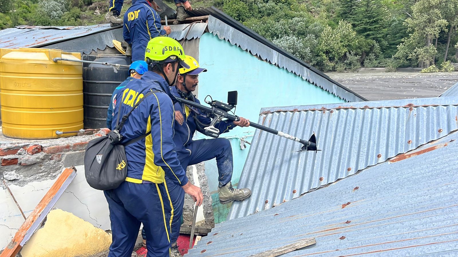 छत की चादर काट कर ऐसे विक्टिम लोकेटिंग कैमरे लगा रहे SDRF के जवान. छत की चादर काट कर ऐसे विक्टिम लोकेटिंग कैमरे लगा रहे SDRF के जवान.