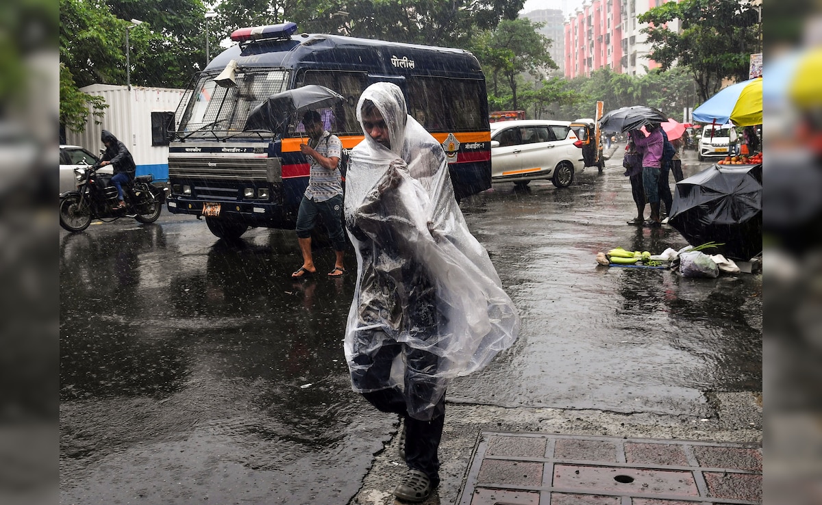 A man protects himself by wrapping a plastic sheet amid rainfall in Mumbai. A man protects himself by wrapping a plastic sheet amid rainfall in Mumbai.