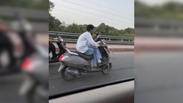 बिना हेलमेट, पैर क्रॉस करके, हाथ में फोन लिए स्कूटी चला रहा था शख्स, ट्रैफिक नियमों की उड़ाई धज्जियां बिना हेलमेट, पैर क्रॉस करके, हाथ में फोन लिए स्कूटी चला रहा था शख्स, ट्रैफिक नियमों की उड़ाई धज्जियां