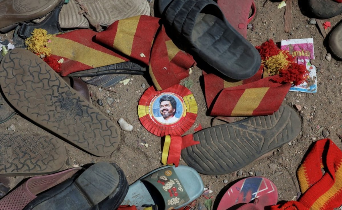 A badge with picture of Vijay lies amid footwears and other belongings left by attendees at the site of a stampede A badge with picture of Vijay lies amid footwears and other belongings left by attendees at the site of a stampede