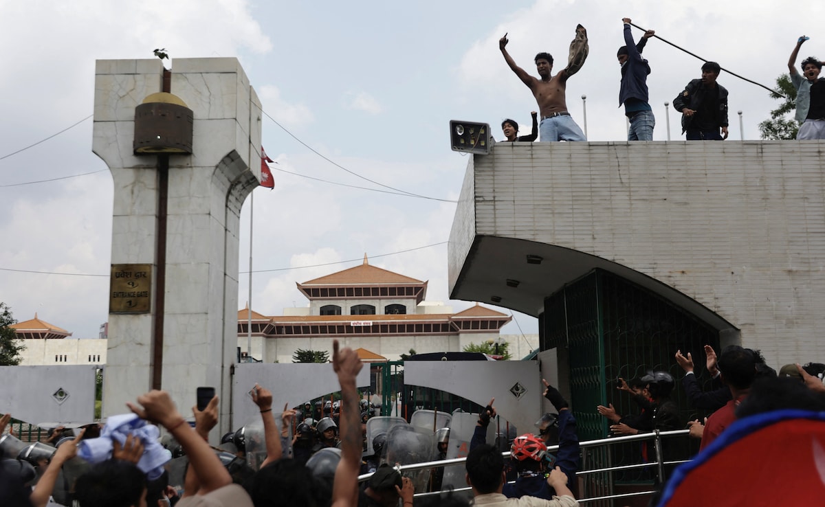 Demonstrators shout slogans as they stand atop the entrance of the Parliament during a protest against corruption and governments decision to block several social media platforms.