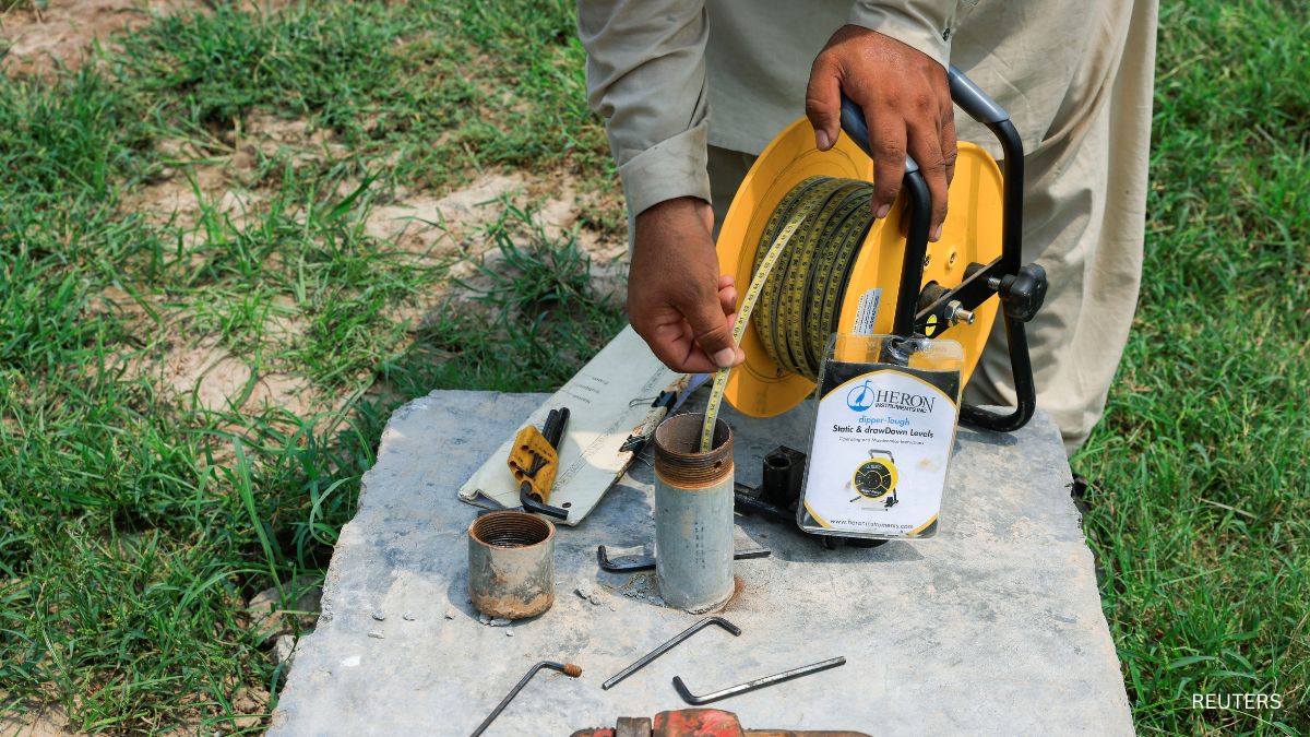 An irrigation department employee uses a dipmeter to check the groundwater level at a borehole in Pakistan An irrigation department employee uses a dipmeter to check the groundwater level at a borehole in Pakistan
