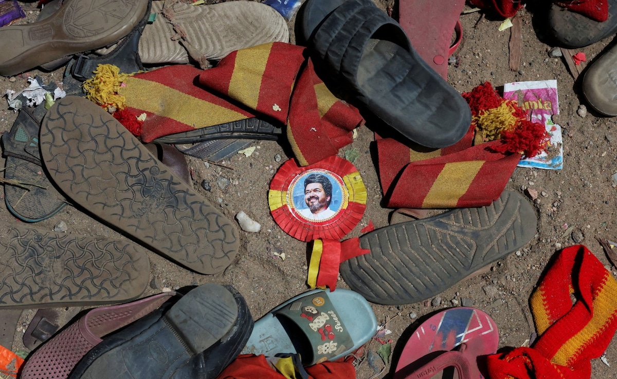 A badge with picture of Vijay lies amid footwears and other belongings left by attendees at the site of a stampede incident A badge with picture of Vijay lies amid footwears and other belongings left by attendees at the site of a stampede incident