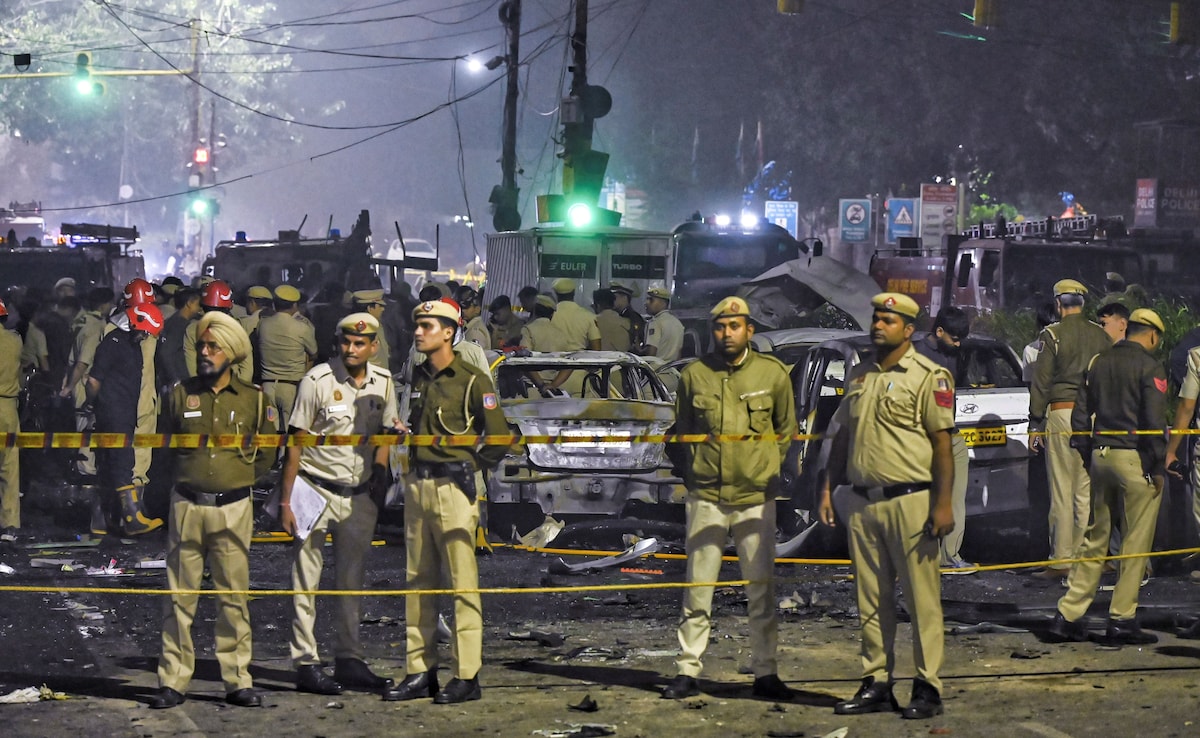 Security personnel at the blast spot that left multiple vehicles in flames. PTI