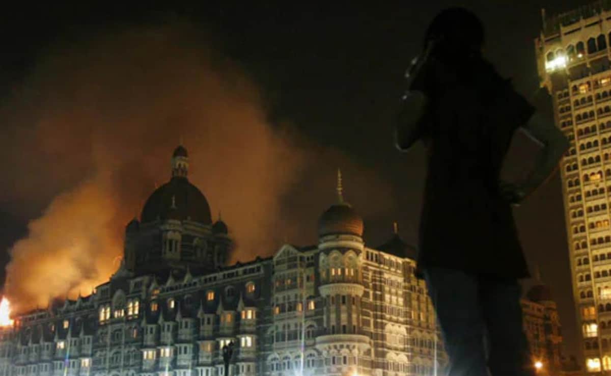 This image shows a reporter talking on her phone as smoke is seen coming from the Taj Hotel in Mumbai, November 27, 2008. 