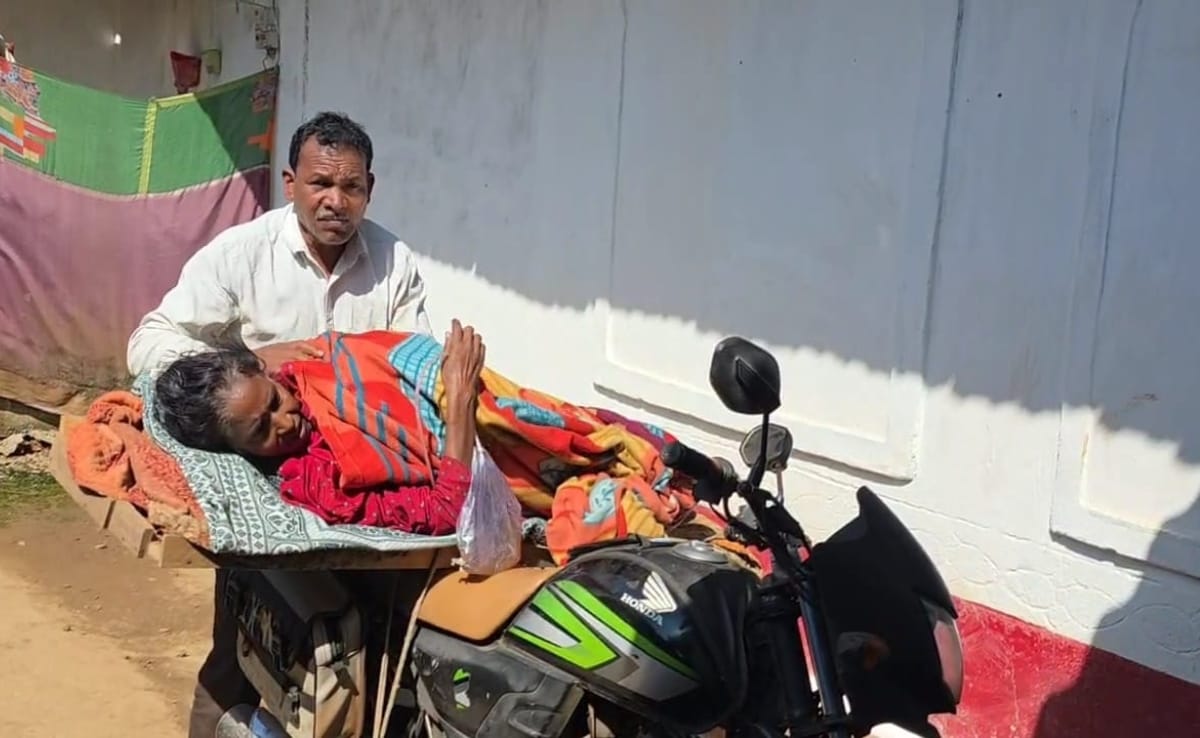 अपनी पत्नी कपुरा मरकाम को इलाज के लिए बाइक पर बने अस्थायी एंबुलेंस में लेकर जाते समलू मरकाम.