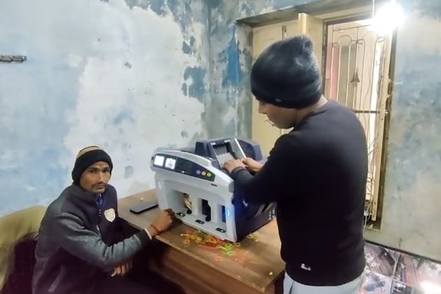 नोट गिनने वाली मशीन से राशि गिनते हुए कर्माचारी
