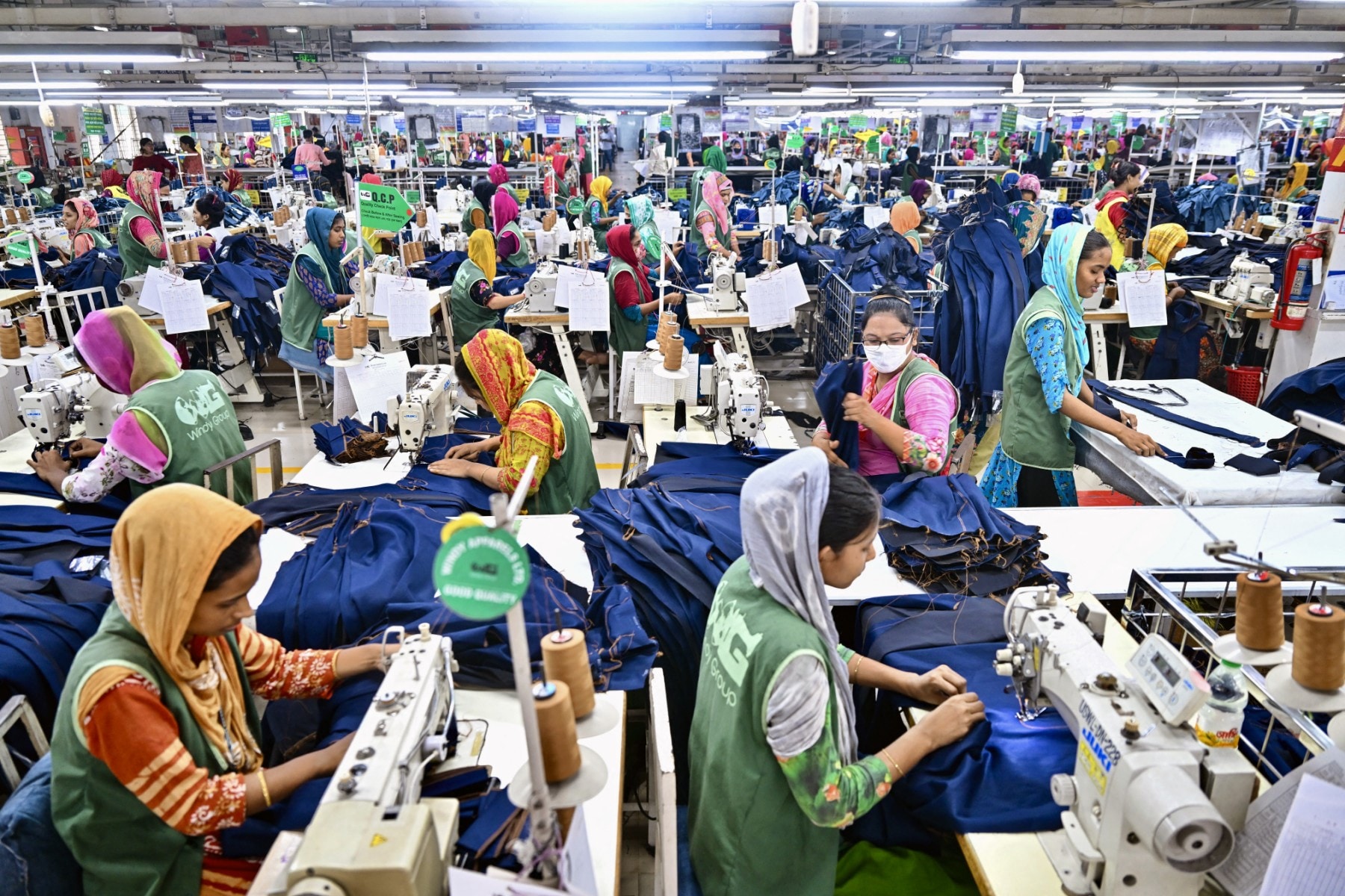 Garment workers tailor clothes at their sewing stations in a garment factory in Tongi, on the outskirts of Dhaka