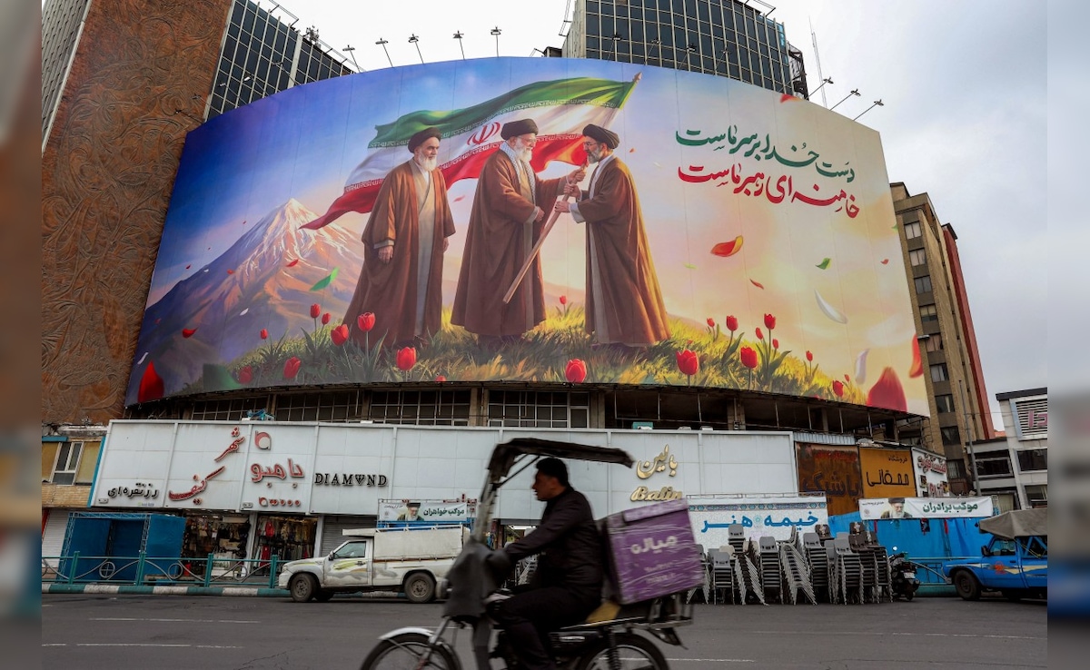 A banner displayed in Tehran shows the late Ali Khamenei handing over national flag to his son. (AFP)