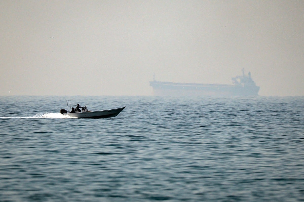  A motorboat cruises along the shore off the town of Al Jeer on the Strait of Hormuz in the northern emirate of Ras Al Khaimah, with a tanker seen in the background, on February 25, 2026.