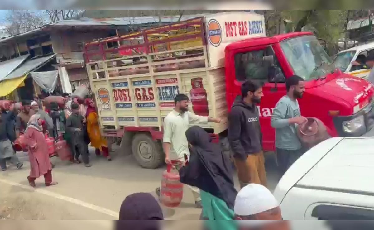 सिलेंडर कंधे पर लादकर गाड़ी का पीछा करते हुए लोग सिलेंडर कंधे पर लादकर गाड़ी का पीछा करते हुए लोग