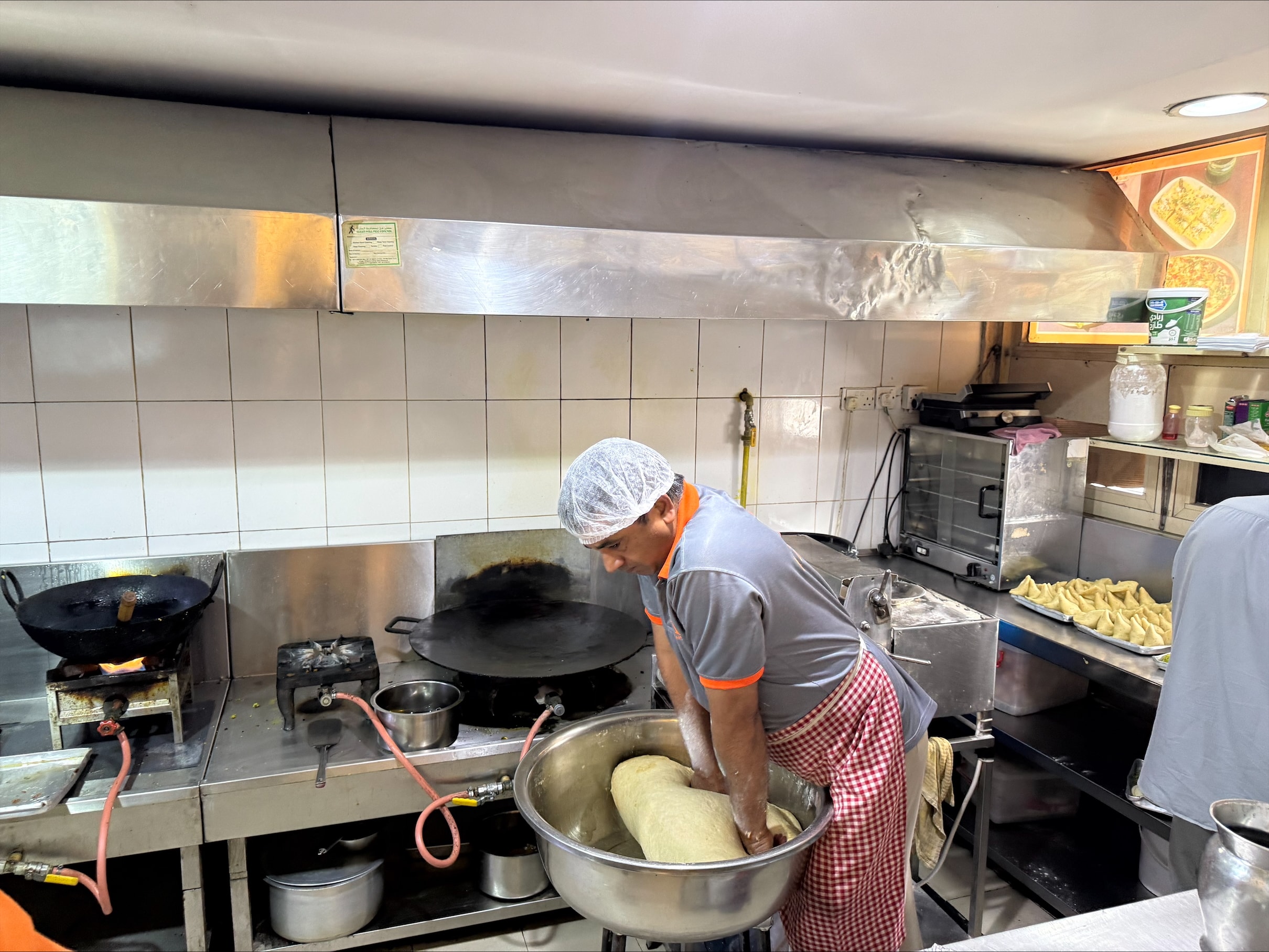 दुबई में खाने-पीने की दुकान में काम करते एक एशियाई नागरिक.