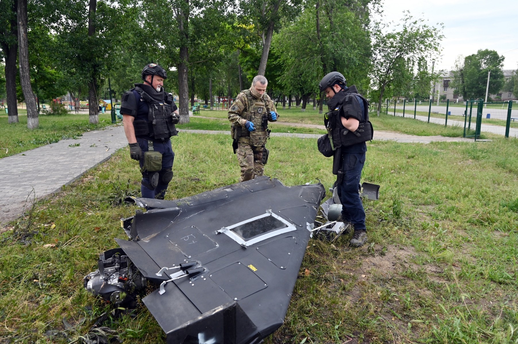 Ukrainian explosives experts and police officers examine parts of a Shahed 136 military drone following an air-attack in Kharkiv on June 4, 2025, amid the Russian invasion of Ukraine