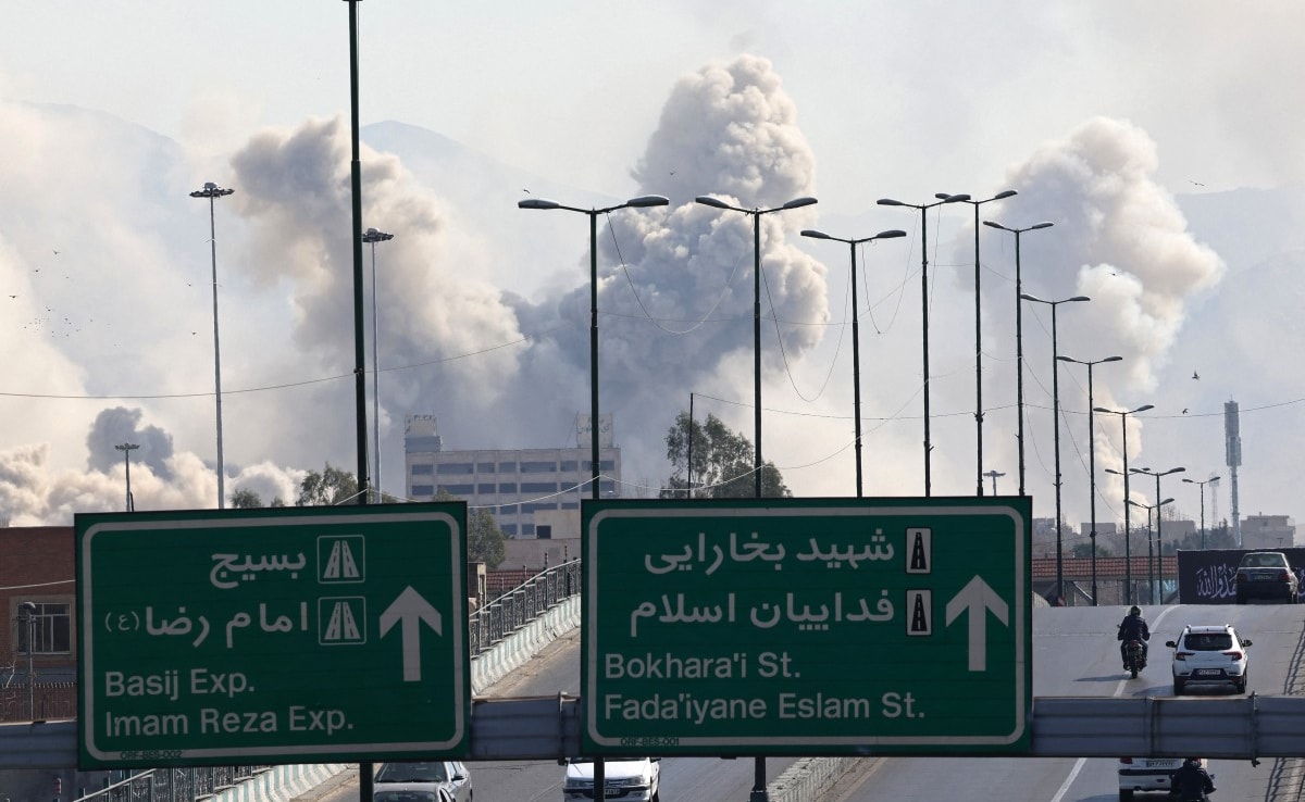 Vehicles drive along an expressway as smoke rises after a strike on Tehran. (AFP)