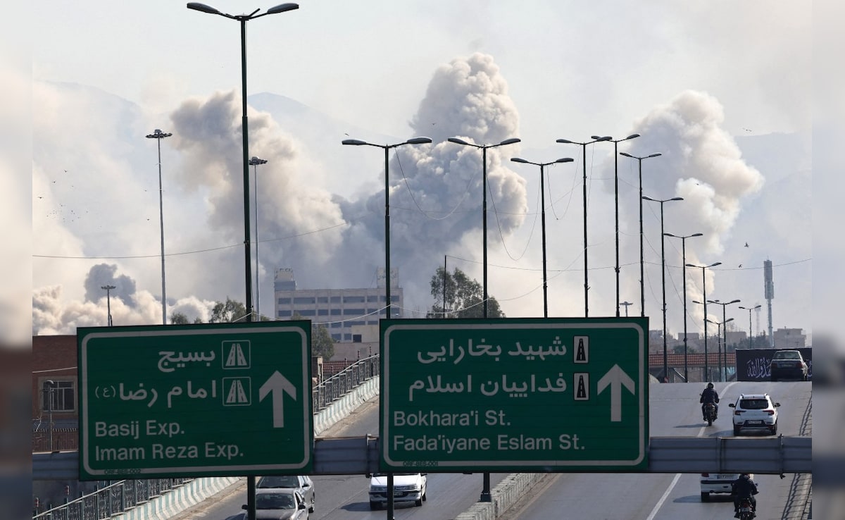 Vehicles drive along an expressway as smoke rises after a strike on Tehran. (AFP)