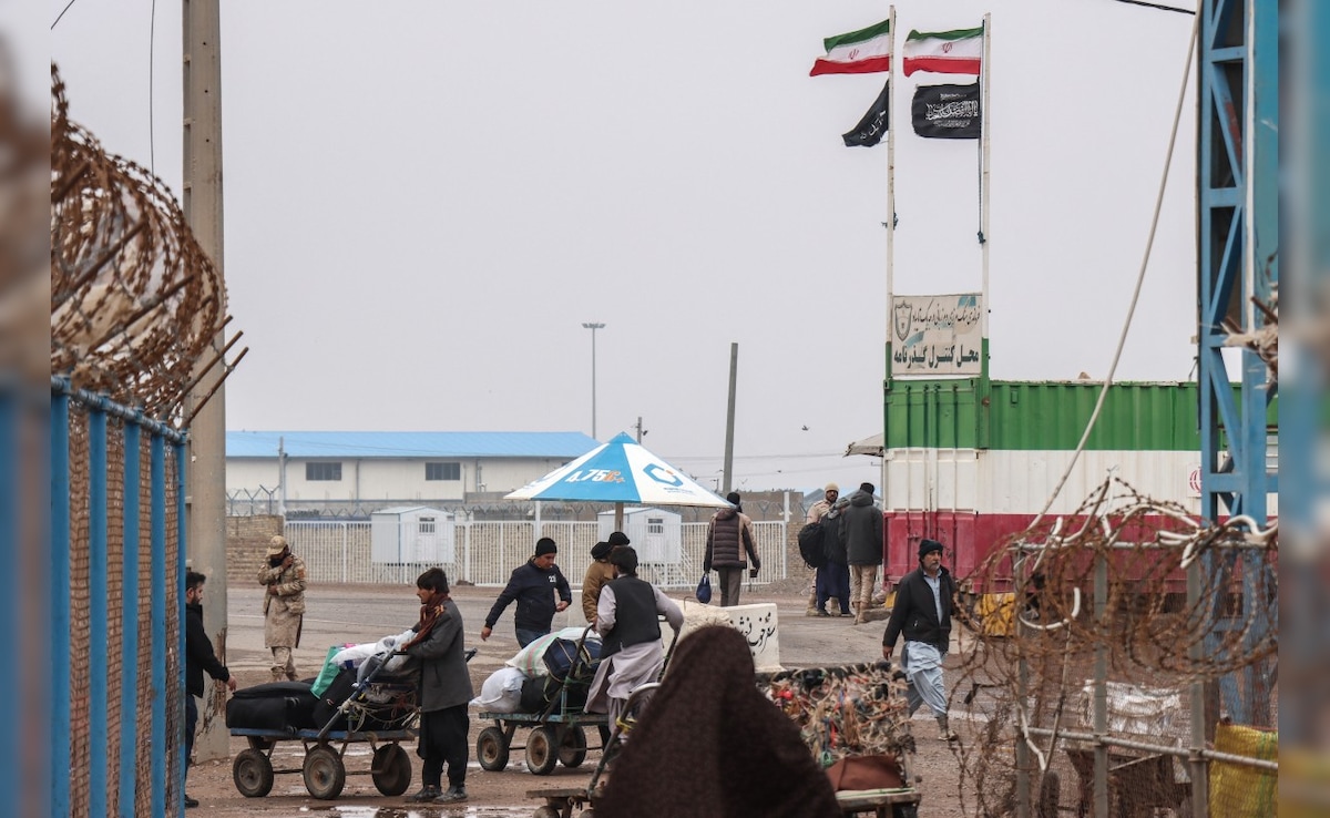 Afghan nationals walk with their belongings upon their arrival from Iran at the Islam Qala border crossing. (AFP)