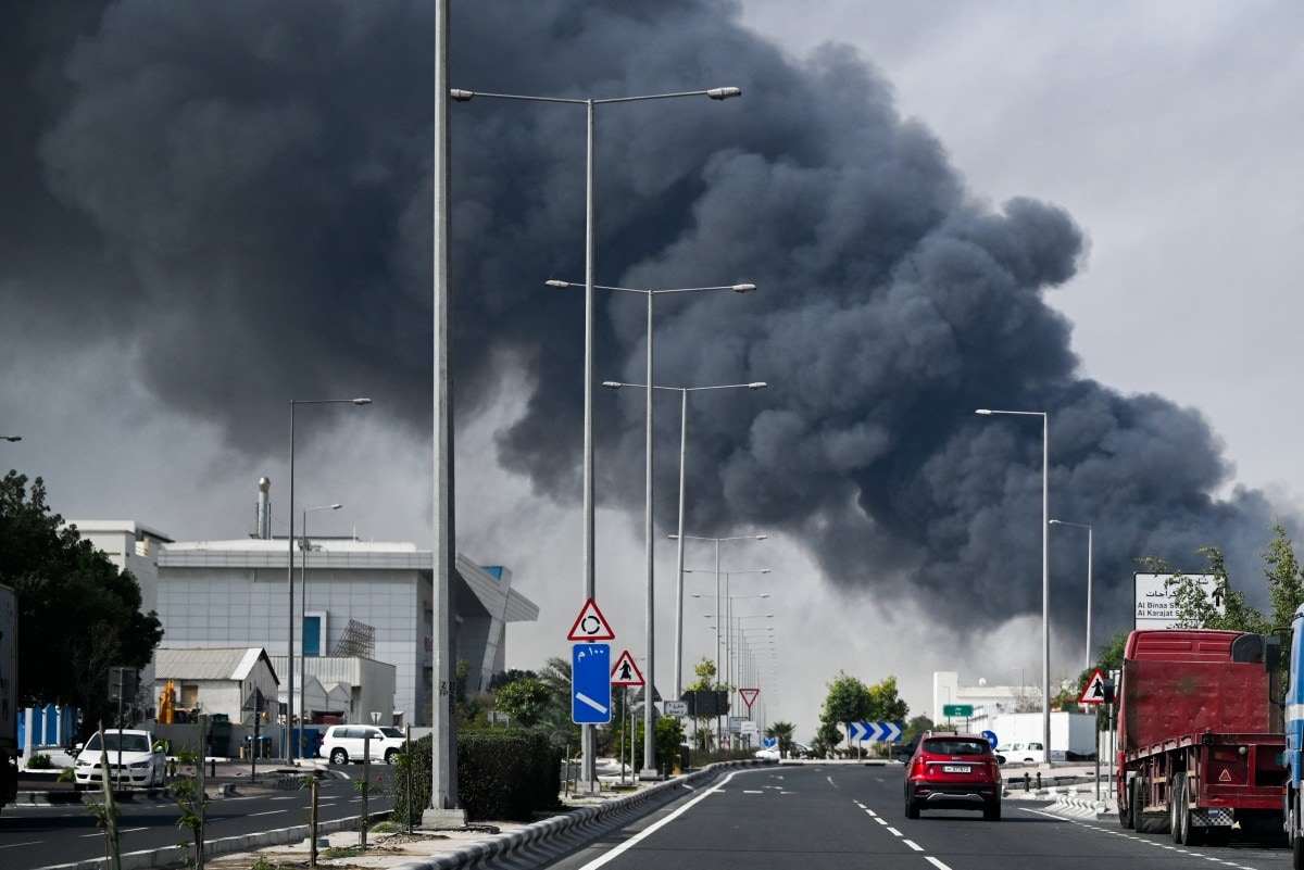 Motorists drive past a plume of smoke rising from a reported Iranian strike in the industrial district of Doha on March 1, 2026. Motorists drive past a plume of smoke rising from a reported Iranian strike in the industrial district of Doha on March 1, 2026.