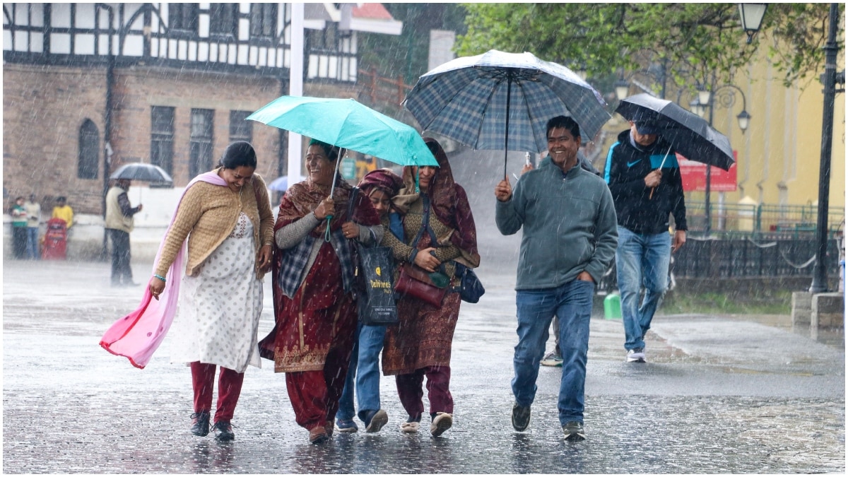 राजधानी शिमला के ऐतिहासिक रिज मैदान पर शुक्रवार को बारिश की फुहारों के बीच टहलते पर्यटक और स्थानीय निवासी.