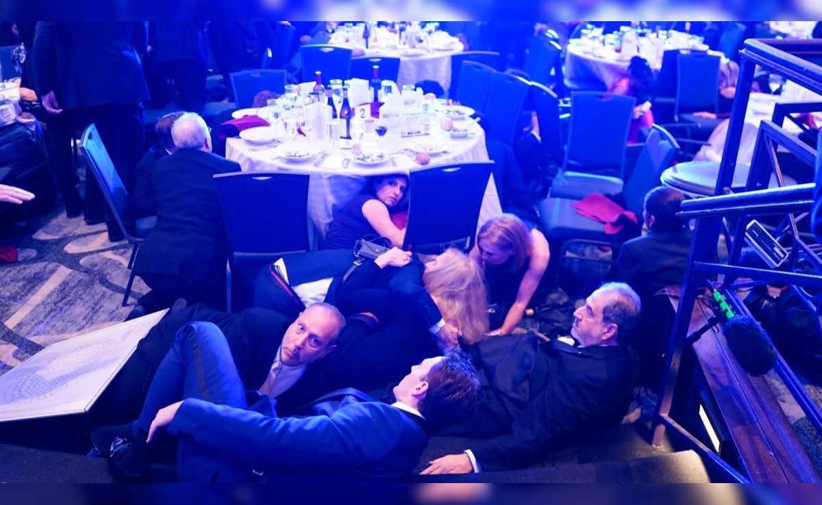 Attendees take cover under tables at the venue.