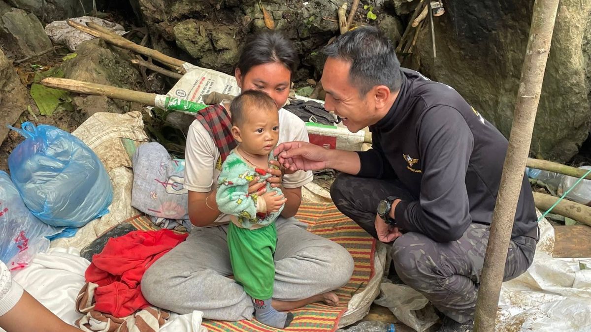 A woman and her baby wait outside the Laos cave as her husband waits to be rescued from inside.