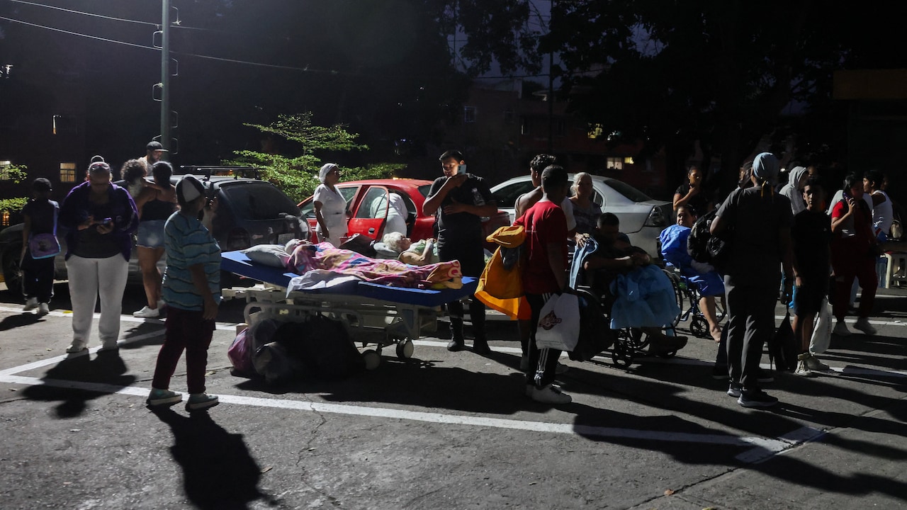 People stand next to others in wheelchairs and hospital beds on the street after an earthquake, in Caracas, Venezuela