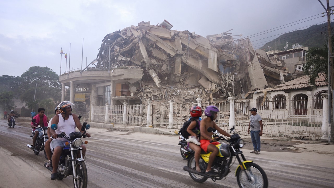People ride past a collapsed building after an earthquake, in La Guaira, Venezuela