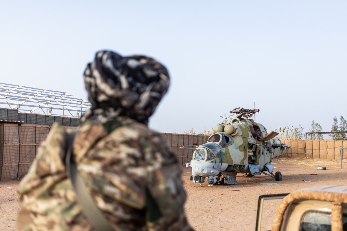 An Azawad Liberation Front (FLA) soldier stands near a damaged Mi-24 helicopter, an attack and troop transportation helicopter, at the former Africa Corps barracks at Camp 2 in Kidal.