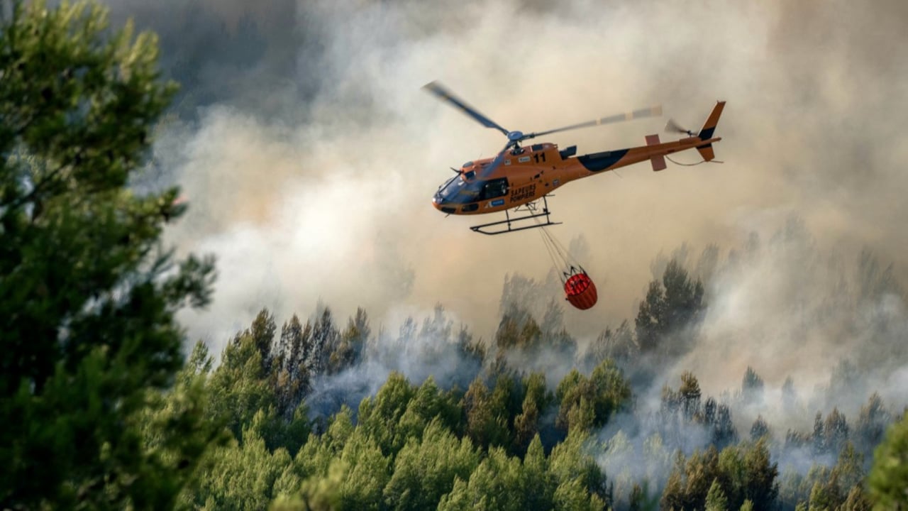 A French firefighting helicopter drops water over burning forest as crews battle wildfires in the Pyrenees-Orientales region of southern France A French firefighting helicopter drops water over burning forest as crews battle wildfires in the Pyrenees-Orientales region of southern France
