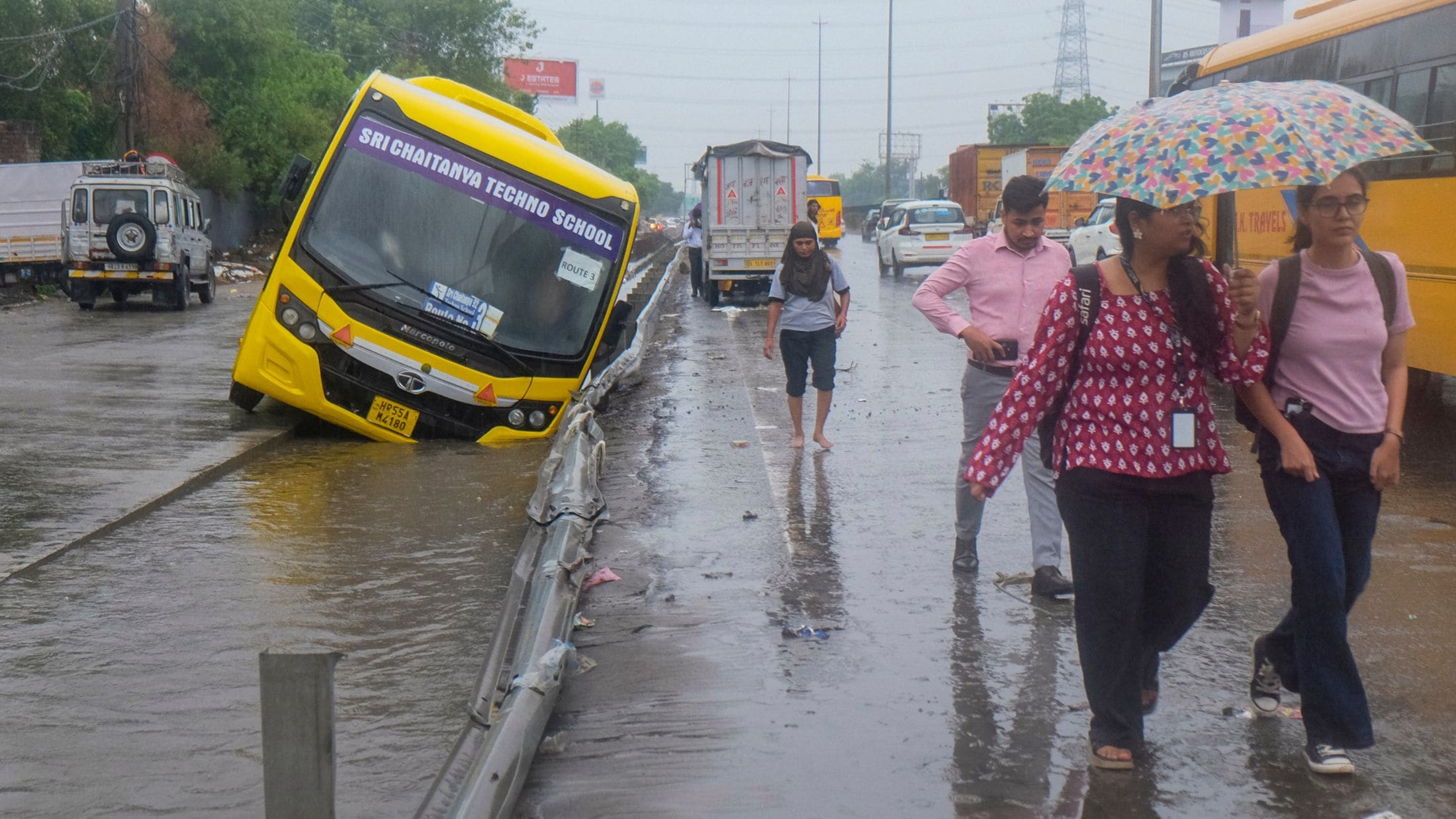 बारिश के बीच सड़क किनारे गड्ढे में फंसी स्कूल बस