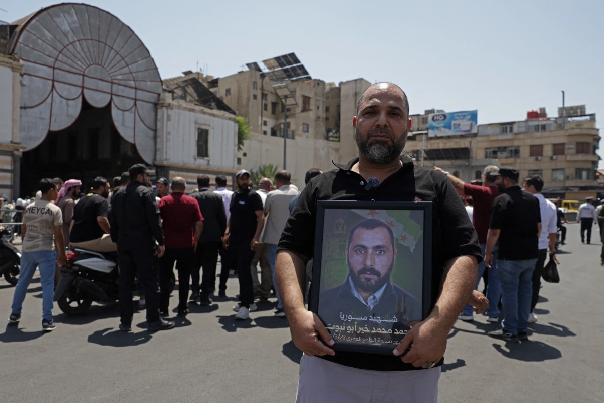 A Syrian carries the picture of his relative, who was killed during the countrys civil war, while celebrating after the court proceedings, in Damascus. A Syrian carries the picture of his relative, who was killed during the countrys civil war, while celebrating after the court proceedings, in Damascus.
