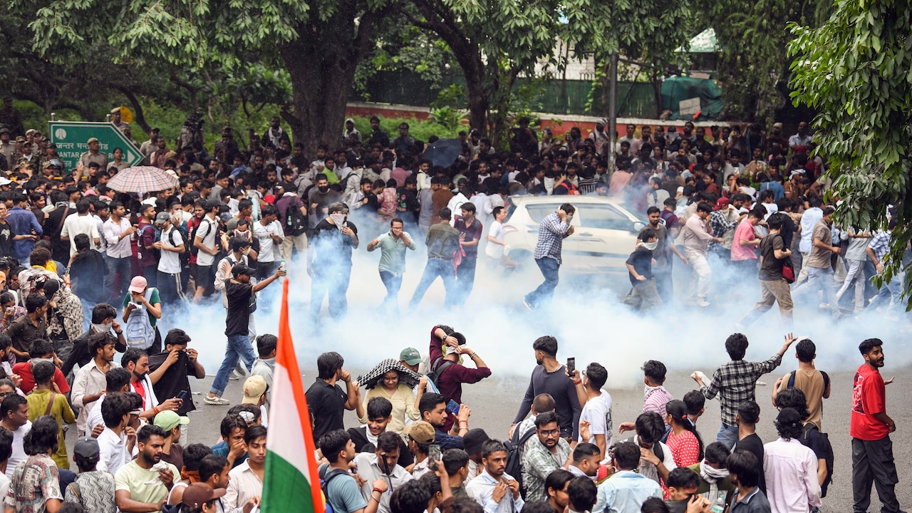 Protesters run as security personnel fire tear gas shells during the protest by Cockroach Janta Party near Jantar Mantar on July 20