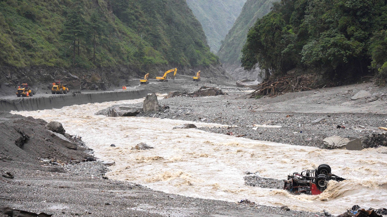 Excavators and loaders in action as rescue workers repair a road leading to Gyirong Port after a mudslide in Gyirong in Tibet