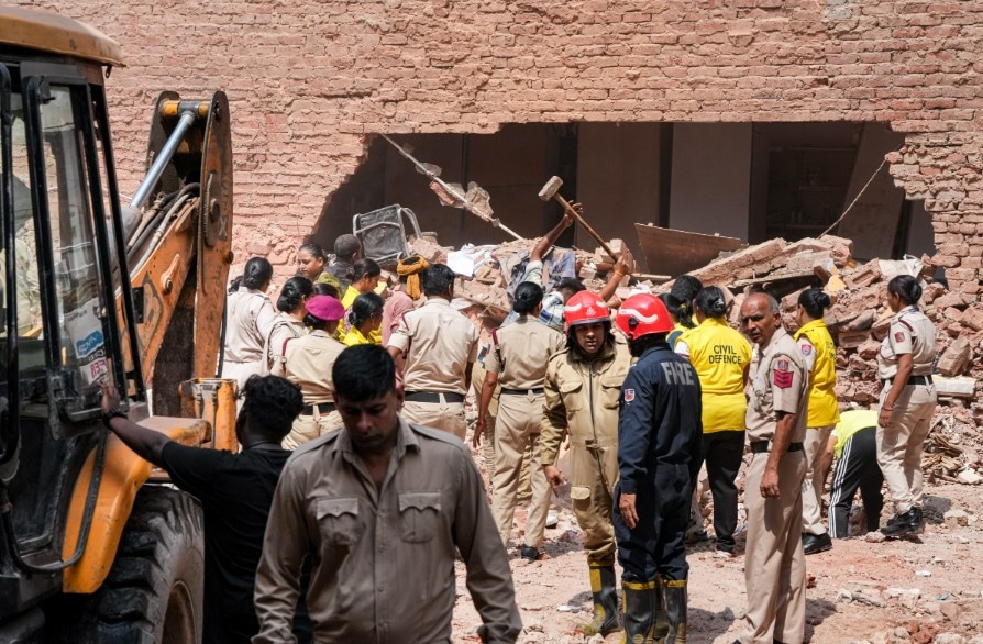 Delhi Fire Service officials, and Civil Defence volunteers coordinate debris clearing efforts following builidng collapse in Satya Niketan