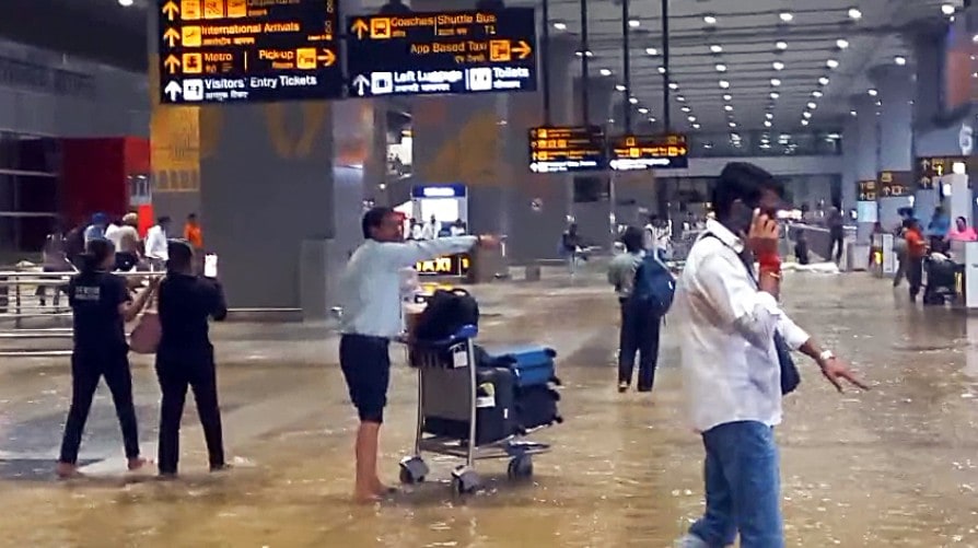 Passengers with their luggage walk through the waterlogged passage at Indira Gandhi International Airport Passengers with their luggage walk through the waterlogged passage at Indira Gandhi International Airport