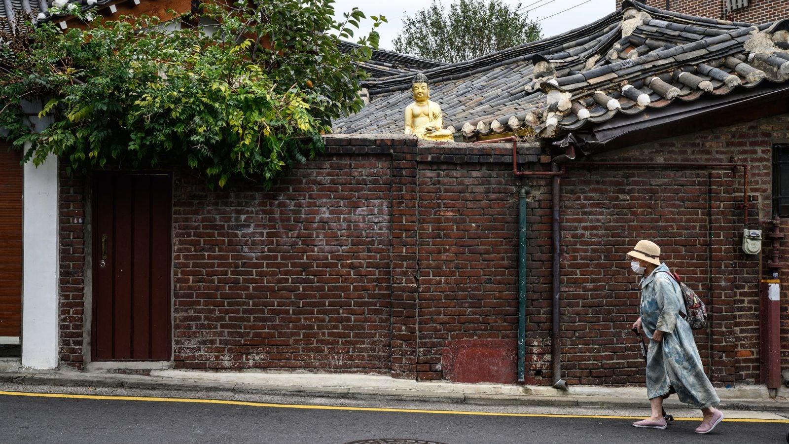 A woman walking past a Buddha statue in the village. 