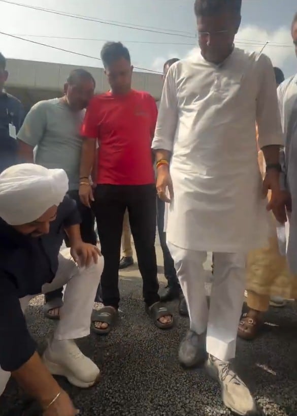 Jarnail Singh bent down to pull at the road edges with the Minister watching the proceedings Jarnail Singh bent down to pull at the road edges with the Minister watching the proceedings